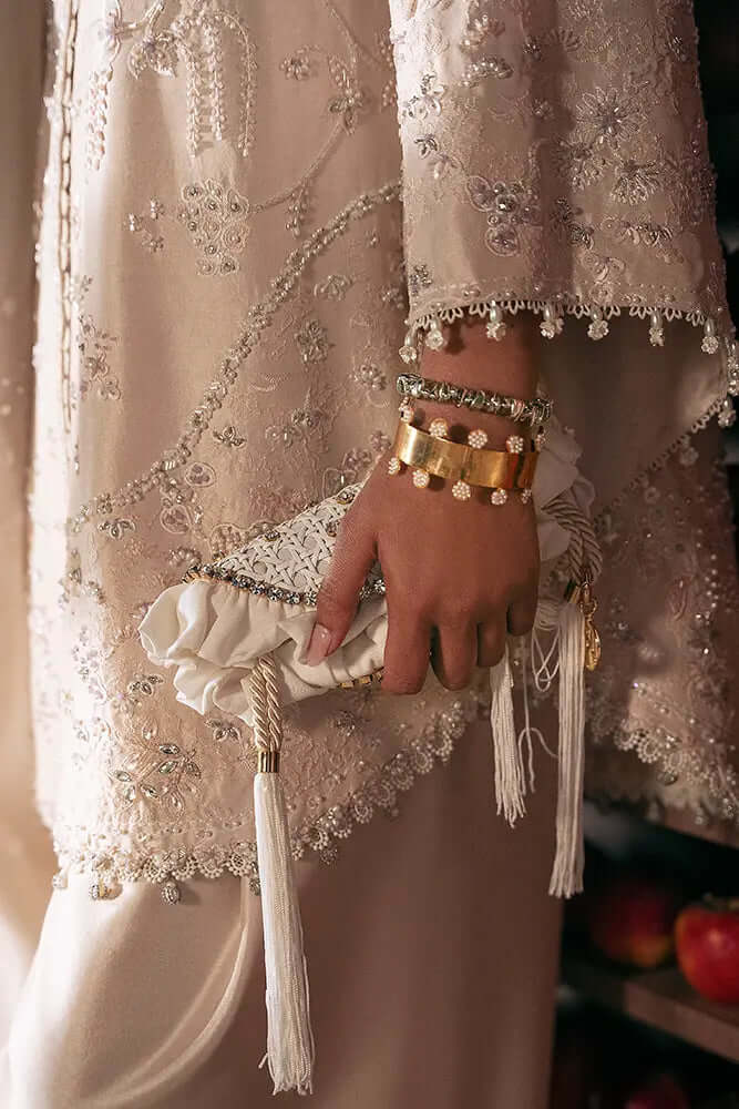 Rhea silk shirt featuring embellishments and a stylish clutch adorned with tassels and accessories.