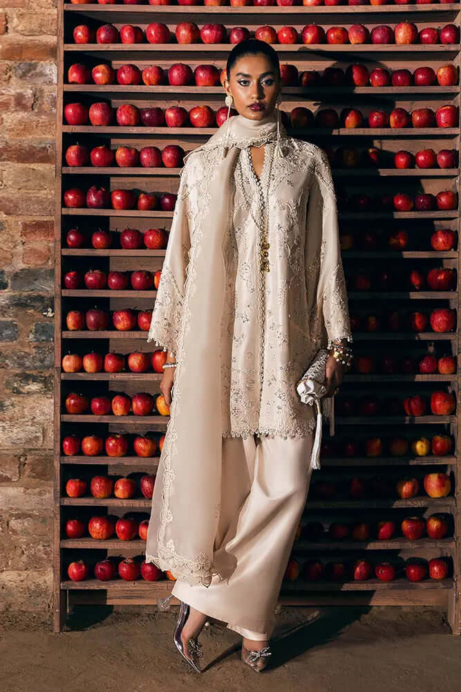 Rhea elegant traditional outfit featuring intricate embroidery and a modern cut, styled with a dupatta against a vibrant apple backdrop.