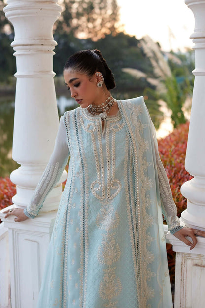 Model wearing Saher elegant sky blue paper lawn kalidaar with intricate embroidery by the water.